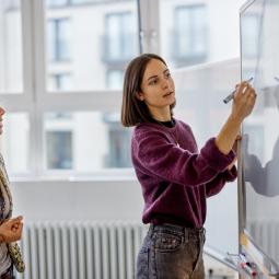 Two women standing in front of whiteboard