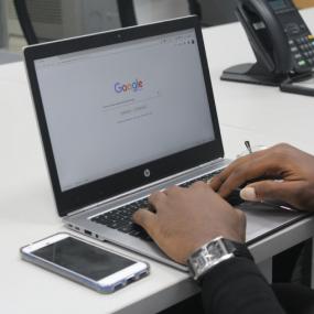 Person typing on a laptop with Google homepage showing